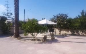 a table and an umbrella next to some trees at Nice Home In Siracusa With Wifi in Siracusa +10 photos