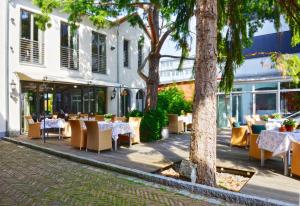 a restaurant with tables and chairs in front of a building at Ringhotel Alpenhof - Patchworkhotel in Augsburg
