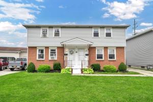 a house with a white door and a grass yard at Cozy Duplex Near BUF International Airport in Cheektowaga