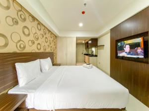 a bedroom with a large white bed and a tv at Homey and Comfort Living Studio Apartment Warhol (W/R) Residences By Travelio in Semarang +7 photos