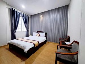 a bedroom with a bed and a chair and a window at Á Đông Hotel DL - by BAY LUXURY in Da Lat +4 photos