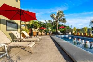 サユリタにあるStunning Ocean Views 2 Pools 10 min walk to beachのラウンジチェアと赤いパラソル付きのプールを併設しています。