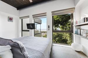 サユリタにあるStunning Ocean Views 2 Pools 10 min walk to beachのベッドと大きな窓のある寝室