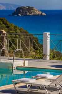 two chairs and a pool with a view of the ocean at Costa Avithos in Svoronata