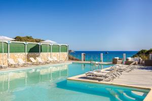 a swimming pool with chairs and the ocean in the background at Costa Avithos in Svoronata