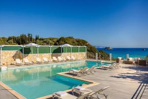a swimming pool with chairs and the ocean in the background at Costa Avithos in Svoronata
