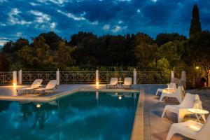 a pool at night with lounge chairs around it at Costa Avithos in Svoronata