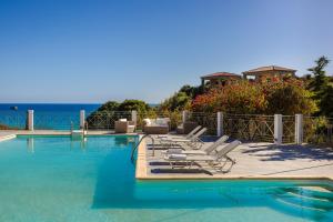 a group of lounge chairs next to a swimming pool at Costa Avithos in Svoronata