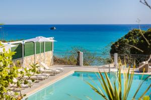 a swimming pool with chairs and the ocean in the background at Costa Avithos in Svoronata