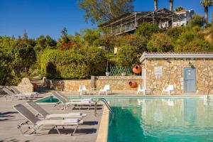 a swimming pool with lounge chairs and a house at Costa Avithos in Svoronata