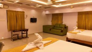 a hotel room with two beds and a couch at Golden Dawn Residency in Tiruvannāmalai