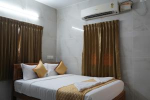a bedroom with a bed with white sheets and yellow pillows at Golden Dawn Residency in Tiruvannāmalai