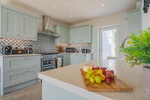 a kitchen with blue cabinets and a cutting board with fruit at Griffin's Rest - Parking, Countryside views in Newquay