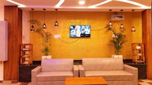 a waiting room with two chairs and a tv on a yellow wall at Golden Dawn Residency in Tiruvannāmalai