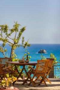a wooden table and chairs with the ocean in the background at Costa Avithos in Svoronata