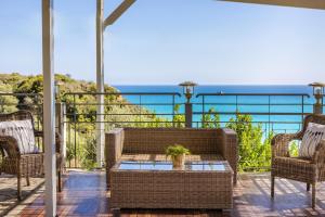 a patio with chairs and a table and the ocean at Costa Avithos in Svoronata