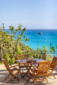 a wooden table and chairs with a view of the ocean at Costa Avithos in Svoronata