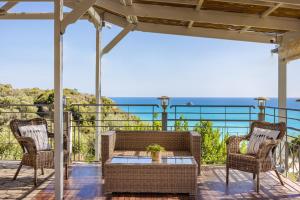 a patio with wicker chairs and a table with a view of the ocean at Costa Avithos in Svoronata