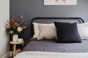 a bedroom with a bed with a vase of flowers at EKhaya - The Barn in Wattamolla