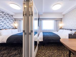 a hotel room with two beds and a desk at APA Hotel Hiroshima Ekimae Stadiumguchi in Hiroshima +80 photos