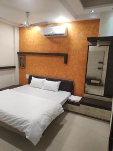 a bedroom with a white bed and a large mirror at Satyabhama Homestay-Pearl - Two BHK Luxury appartment in Indore