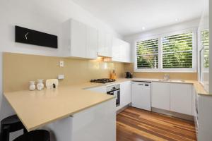 a kitchen with white cabinets and a counter top at Lane by the Bay - Centrally located 2 bed modern Townhouse in Byron Bay