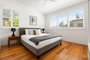 a bedroom with a bed with white walls and windows at Lane by the Bay - Centrally located 2 bed modern Townhouse in Byron Bay