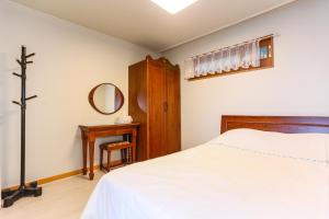 a bedroom with a bed and a mirror and a table at Four Season Pension in Seogwipo
