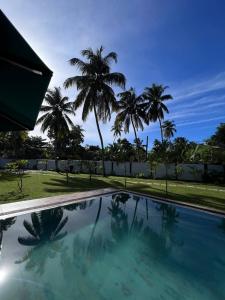 a swimming pool with palm trees in the background at Cozy Villa in Hikkaduwa