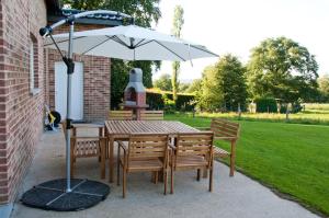a wooden table and chairs with an umbrella at Gite L'Armandier in Sart-lez-Spa