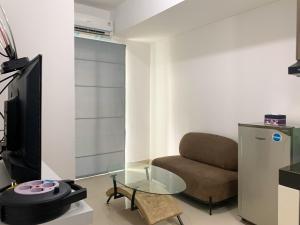 a living room with a couch and a glass table at Homey and Simply 2BR at Serpong Garden Apartment By Travelio in Tangerang