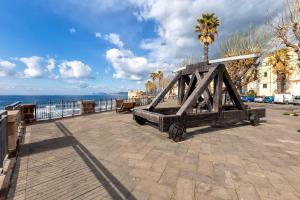 een houten brug naast de oceaan met een palmboom bij Non dire Gatto - Elegant Rooftop in Alghero