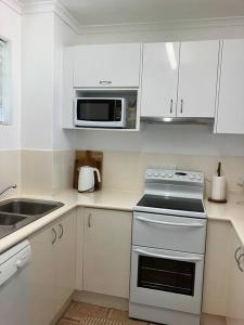 a white kitchen with a stove and a microwave at Casa Palma in Palm Cove +5 photos