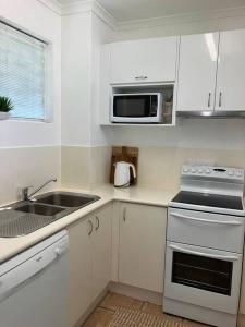 a white kitchen with a sink and a microwave at Casa Palma in Palm Cove
