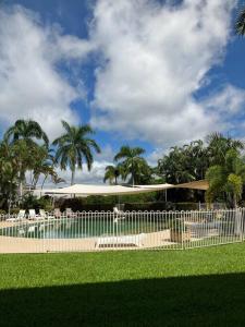a fence in front of a building with chairs and palm trees at Casa Palma in Palm Cove
