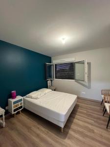 a bedroom with a white bed and a blue wall at Gites de Landuzire, Sleeps 14 in Saint-Genest-Lerpt