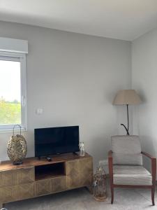 a living room with a flat screen tv and a chair at Gites de Landuzire, Sleeps 14 in Saint-Genest-Lerpt