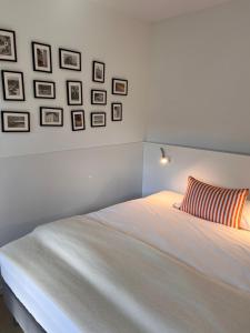 a white bed with a striped pillow and pictures on the wall at Sonniges Hinterhaus OG Innenstadt in Osnabrück