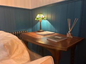 a bedroom with a table with a lamp and a bed at Clachamish House in Portree