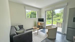 ein Wohnzimmer mit einem Sofa, Stühlen und einem TV in der Unterkunft La maison neuve in Veyrac