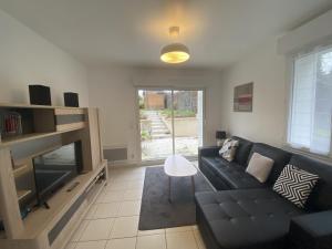 ein Wohnzimmer mit einer schwarzen Couch und einem Fernseher in der Unterkunft Maison rénovée avec cuisine équipée à La Roche-Posay - FR-1-541-148 in La Roche-Posay