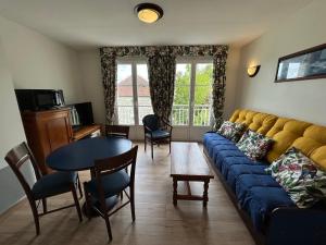 a living room with a blue couch and a table at T2 avec piscine et WiFi à 200m des Thermes - FR-1-541-150 in La Roche-Posay