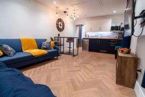 a living room with a blue couch and a kitchen at Hidden Home in Haywards Heath