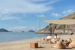 two people sitting under a tent on the beach at Six Senses Con Dao - Turtle Island Paradise in Con Dao