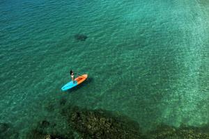a person standing in the water with a surfboard at Six Senses Con Dao - Turtle Island Paradise in Con Dao