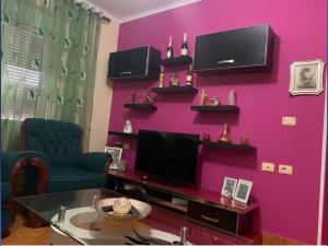 a living room with a pink wall with a tv at Malsi 2 Bedrooms Apartment in Vlorë +5 photos