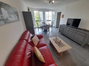 a living room with a red couch and a table at T2 lumineux avec Wi-Fi au centre de La Roche-Posay - FR-1-541-124 in La Roche-Posay