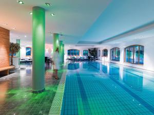 a woman is standing in front of a swimming pool at Defereggental Hotel & Resort in Sankt Veit in Defereggen