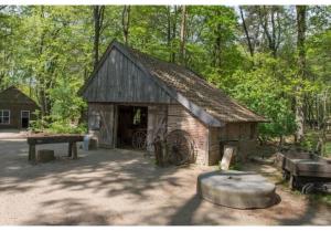 an old barn with a wheel in front of it at Grijze Veen 8-person bungalow in Voorthuizen