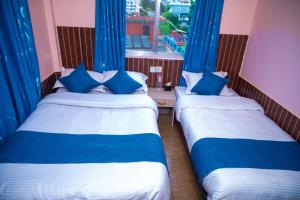 2 łóżka w pokoju z niebieskimi zasłonami i oknem w obiekcie Hotel White Yak w mieście Pokhara